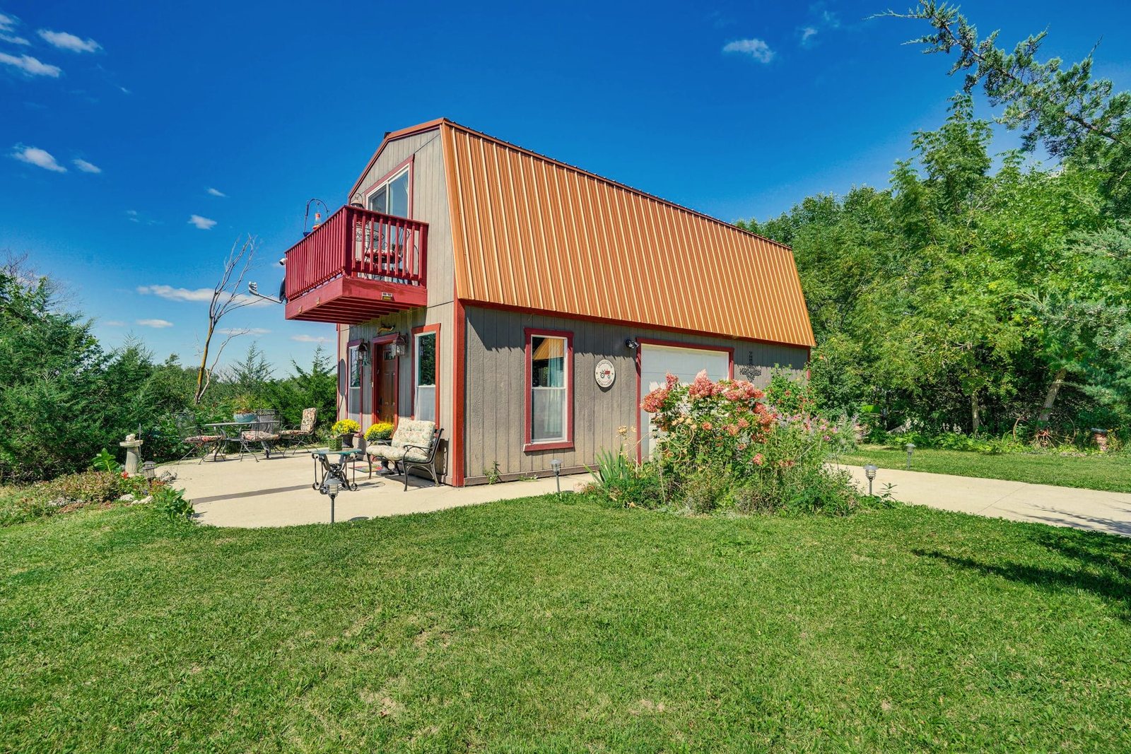 Barn-style cabin with a red balcony and flower garden at Eden Garden House Retreat, a home BookedMore co-hosts in Cokato, Minnesota