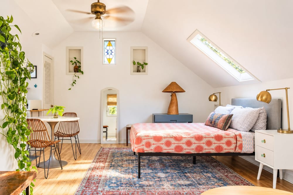 Bright attic bedroom with a skylight, boho decor and a bistro table, a home BookedMore co-hosts