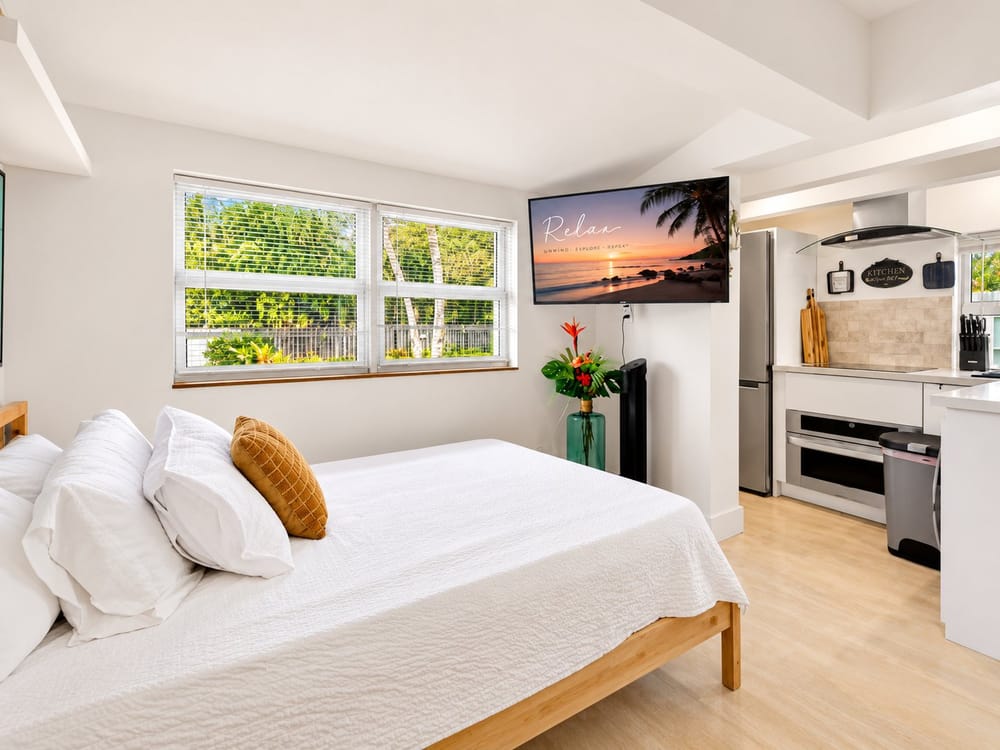 Freshly made bed with crisp white linens in a bright studio, a home BookedMore co-hosts