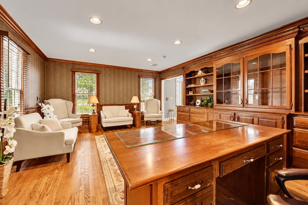 Wood-paneled home office with built-in cabinetry, a large desk and a sitting area, a home BookedMore co-hosts