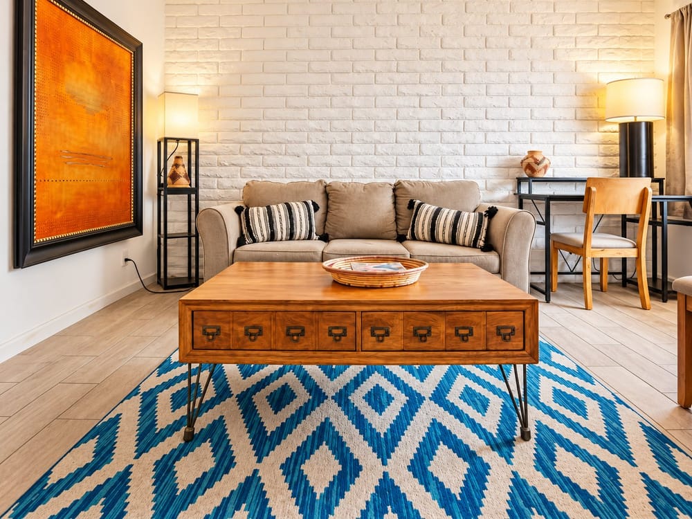 Mid-century living room with a white brick wall and a carved wood coffee table at Westgate Villa I, a home BookedMore co-hosts in Phoenix, Arizona
